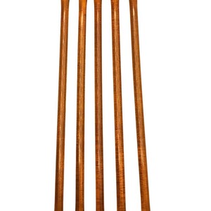 May include: Four individual honey sticks, each a translucent amber color, are arranged vertically in a row against a white background.