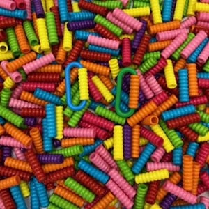 以下が含まれることがあります： カラフルなプラスチック製の鉛筆グリップの山。グリップはらせん状で、赤、オレンジ、黄色、緑、青、紫、ピンクなど、さまざまな色があります。