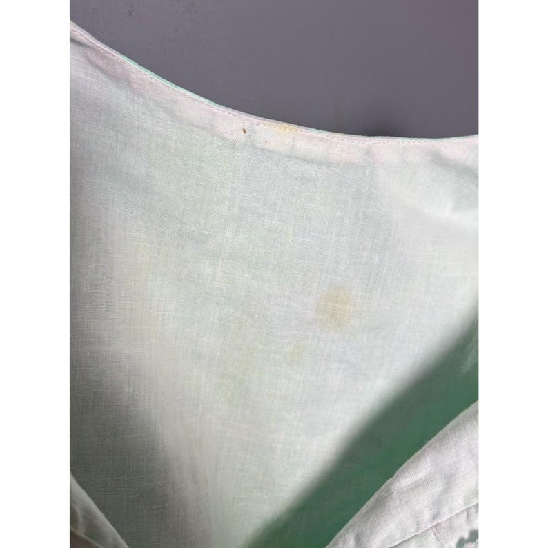 May include: A white ceramic mug with a black handle and the text "But First, Coffee" in a black, handwritten-style font. The mug is on a white surface.