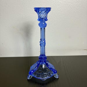 May include: A white ceramic mug with a black handle and the text "But First, Coffee" in a black, handwritten-style font. The mug is on a white surface.