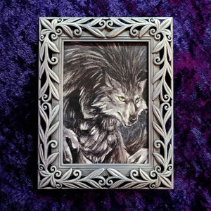 Puede incluir: Una ilustración enmarcada en blanco y negro de un lobo con una expresión amenazante. Los ojos del lobo brillan de color amarillo.