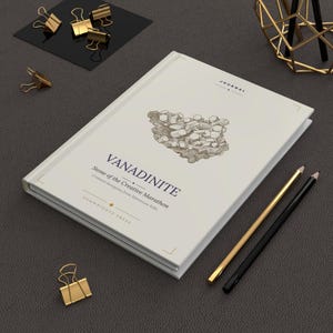 Może przedstawiać: Biały notatnik z tytułem "VANADINITE" i tekstem "Stone of the Creative Marathon" jest wyświetlany. Notatnik ma szczegółową ilustrację formacji kamiennej. Obecne są również złote spinacze i ołówki.