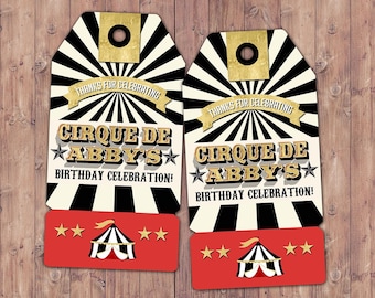 Pode incluir: Duas etiquetas de presente com tema de circo, com fundo listrado em preto e branco e detalhes dourados. As etiquetas dizem "CIRQUE DE ABBY'S BIRTHDAY CELEBRATION!" e apresentam um gráfico de tenda de circo em uma faixa vermelha.