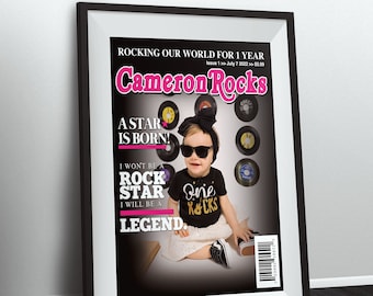 Puede incluir: Una portada de revista con el título "Cameron Rocks" en letras rosas. La portada presenta a una niña pequeña con gafas de sol y una camiseta negra con texto de purpurina dorada que dice "One Rocks". La portada también presenta una foto en blanco y negro de la niña pequeña y un fondo negro con texto de purpurina dorada que dice "A Star Is Born!" y "I Won't Be A Rock Star I Will Be A Legend."