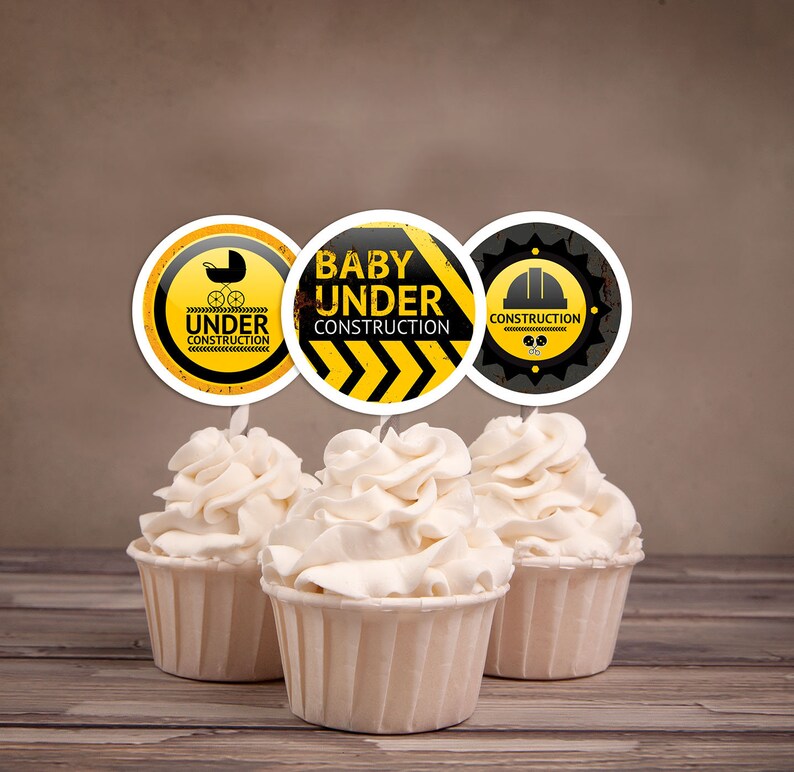 Puede incluir: Tres adornos para cupcakes amarillos y negros con el texto "Baby Under Construction" y un gr&aacute;fico de un trabajador de la construcci&oacute;n.