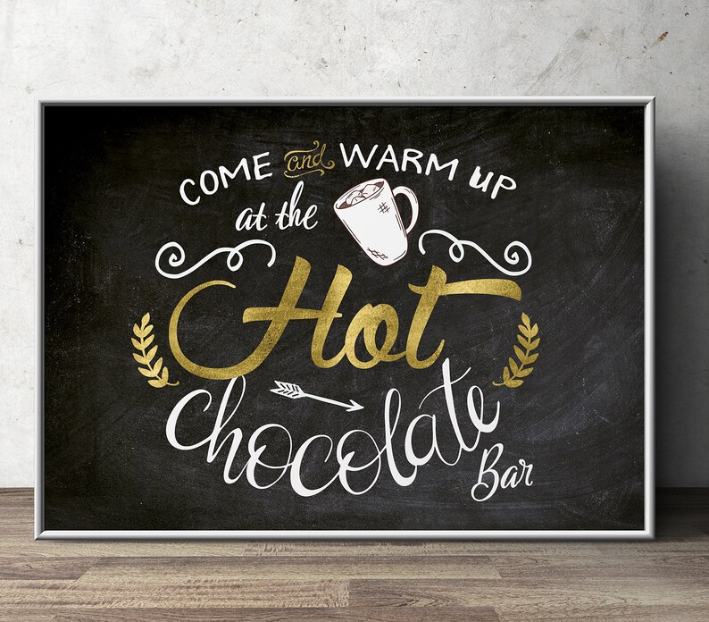 May include: Black chalkboard sign with white text that reads "Come and warm up at the Hot Chocolate Bar". The sign has a gold glitter finish and a white mug with marshmallows on top.