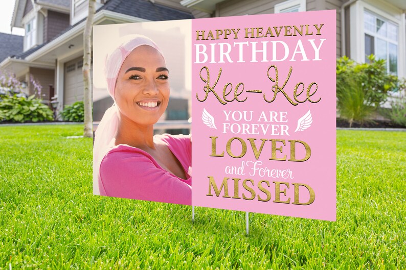 May include: Pink memorial sign with a photo of a woman wearing a pink headscarf. The sign reads "Happy Heavenly Birthday Kee-Kee You Are Forever Loved and Forever Missed".