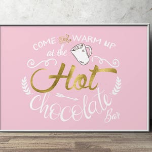 May include: Pink sign with gold lettering that reads "Come and warm up at the Hot Chocolate Bar". A gold mug with marshmallows is pictured above the text.