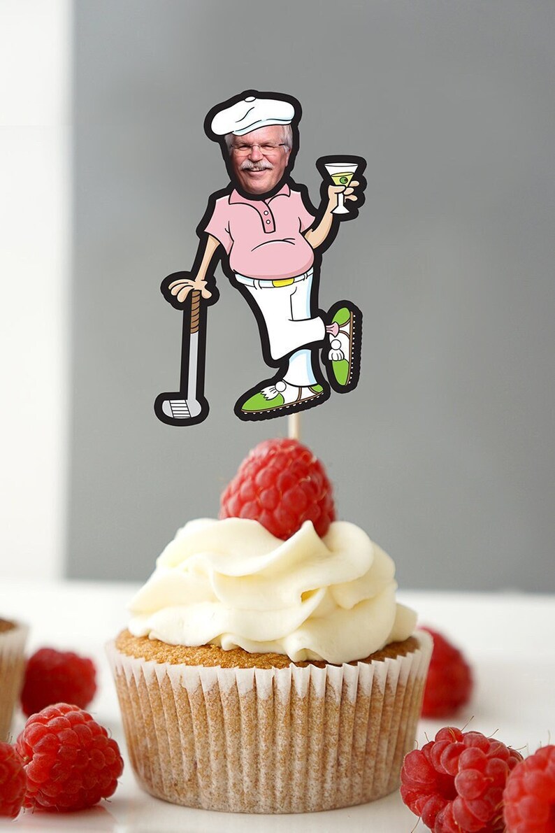 May include: A cupcake with white frosting and a fresh raspberry. A cartoon golf-themed cake topper depicts a man in a pink shirt, white trousers, and a golf club, holding a martini. The cupcake is in a paper case.