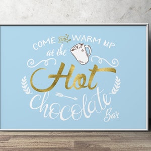 May include: A blue and white sign with gold lettering that says "Come and warm up at the Hot Chocolate Bar". The sign features a drawing of a mug of hot chocolate with marshmallows.