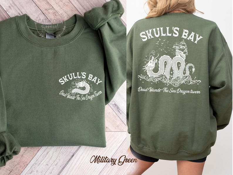May include: Military green sweatshirt with white text and graphic. The front features "SKULL'S BAY" and a dragon design. The back displays the same text and a detailed dragon and ship illustration. The text "Dead Islands The Sea Dragon Tavern" is also present.
