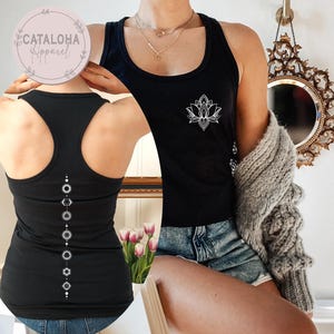 May include: Two black tank tops with white designs. One tank top features a lotus flower design, while the other has a vertical line of circles and geometric shapes.