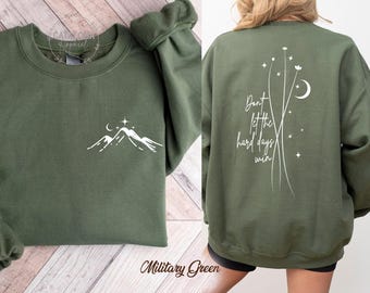 May include: A green sweatshirt with a white mountain and stars design on the front and the text "Don't let the hard days win" on the back.