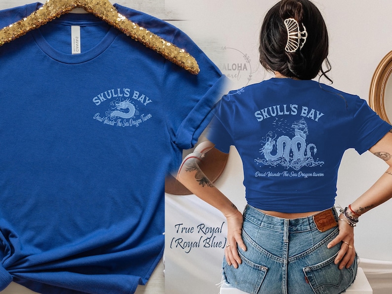 May include: Royal blue t-shirt with the text "SKULL'S BAY" and a sea dragon design. The shirt also has the text "Dead lands The Sea Dragon luver". The shirt is displayed on a gold hanger.