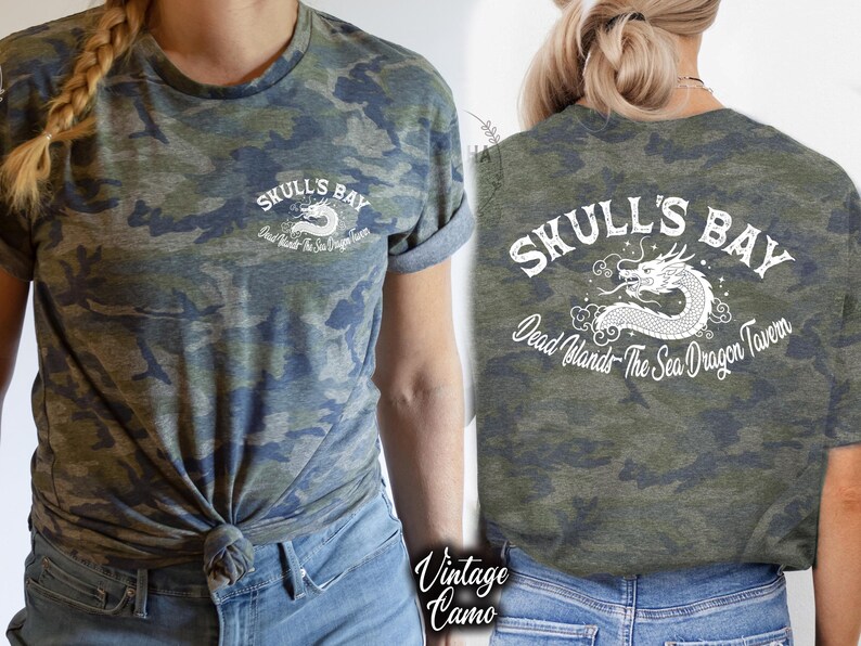 May include: A camouflage-patterned t-shirt with the text "Skull's Bay" and a dragon graphic. The shirt is olive green, blue, and gray. The back of the shirt also features the text "Skull's Bay" and a dragon graphic.