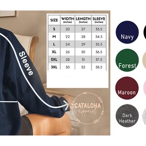 K&ouml;nnte beinhalten: Gr&ouml;&szlig;entabelle f&uuml;r einen Pullover mit Ma&szlig;en in Zoll. Die Tabelle zeigt Breite, L&auml;nge und &Auml;rmell&auml;nge f&uuml;r die Gr&ouml;&szlig;en S, M, L, XL, 2XL und 3XL. Die Tabelle befindet sich auf einem braunen Hintergrund mit wei&szlig;em Rand. Unter der Tabelle befinden sich Farbmuster f&uuml;r den Pullover in Marineblau, Schwarz, Rot, Waldgr&uuml;n, Sand, Wei&szlig;, Rotbraun, Hellrosa, Sportgrau, Dunkelgrau und Asche.