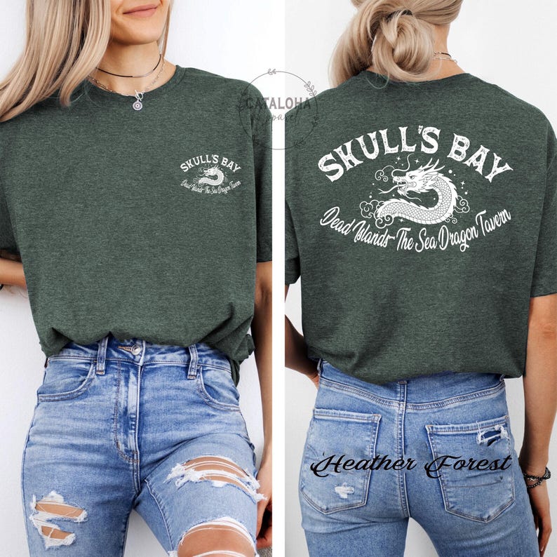 May include: Dark green t-shirt with the text "SKULL'S BAY" and a white dragon graphic on the front and back. The back of the shirt also includes the text "Dead Islands The Sea Dragon Tavern". The shirt is paired with blue jeans.