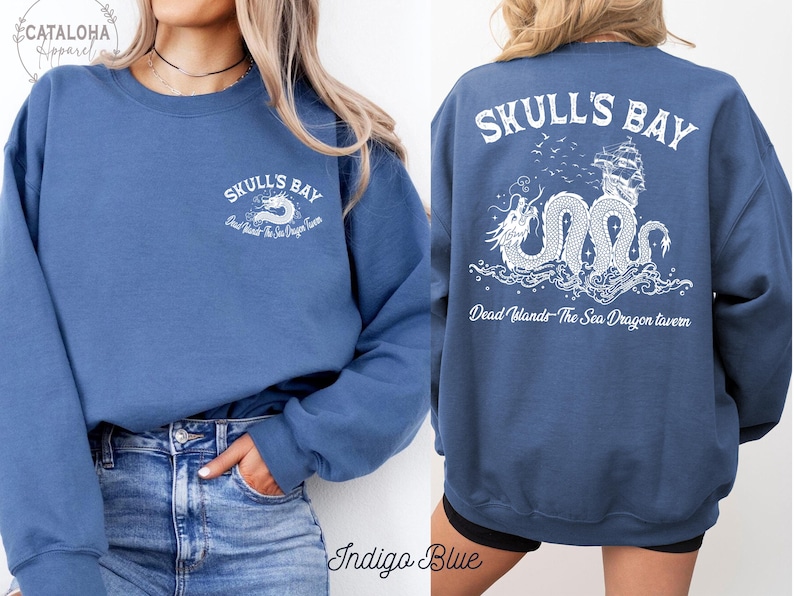 May include: Indigo blue sweatshirt with white graphic text and a dragon design. The front features "Skulls Bay" and "Dead Islands The Sea Dragon Tavern". The back displays a detailed dragon, ship, and text "Skulls Bay" and "Dead Islands The Sea Dragon Tavern".