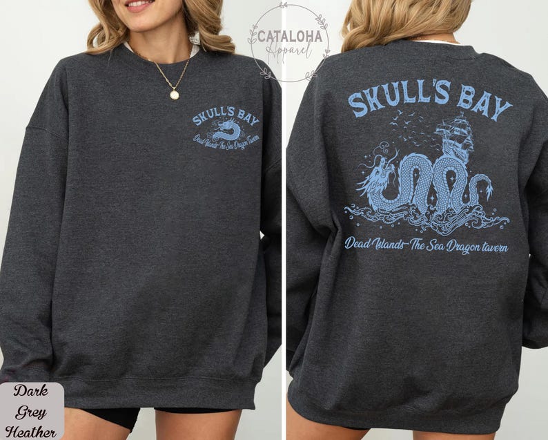 May include: Dark grey heather sweatshirt with "Skull's Bay" text and a sea dragon graphic in light blue on the front and back. The back design includes a ship and the text "Dead Islands - The Sea Dragon Tavern".