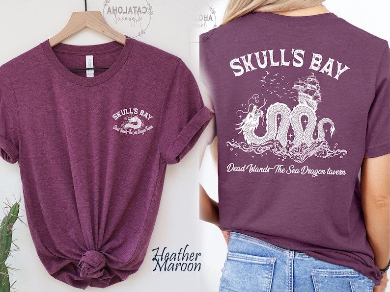 May include: Heather maroon t-shirt with "Skull's Bay" text and a dragon graphic on the front and back. The back design includes a ship and the text "Dead Islands The Sea Dragon tavern".