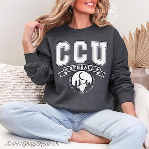Pode incluir: Camisola cinza escuro mesclada com o texto "CCU SUNBALL" em letras brancas. Abaixo, uma faixa com estrelas e as palavras "THE PACK OF DEVILS - LUNATHION". A camisola &eacute; de gola redonda e mangas compridas.