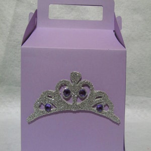 May include: A lavender-colored cardboard box with a handle. The box has a silver glitter crown with purple jewels on the front.