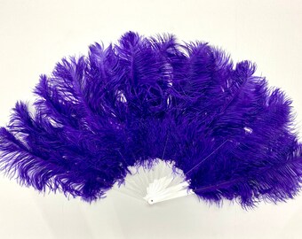 May include: A purple ostrich feather fan with a white handle. The fan is fully extended and the feathers are spread out.