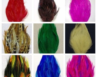 May include: Assortment of nine feather plumes in various colors, including red, brown, pink, green, beige, orange, blue, and purple. The feathers are arranged in a grid pattern.