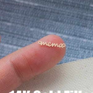 Puede incluir: Primer plano de un dedo con un collar de oro relleno con la palabra "mama" escrita en cursiva.