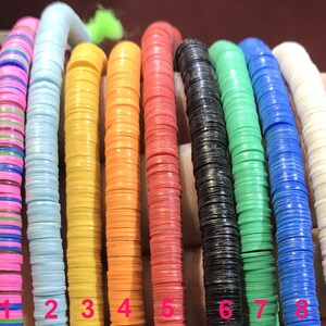 May include: Nine strands of colorful round plastic beads, each strand is a different color, including pink, light blue, yellow, orange, red, black, green, blue, and white. The beads are arranged in a row, numbered 1 through 9.