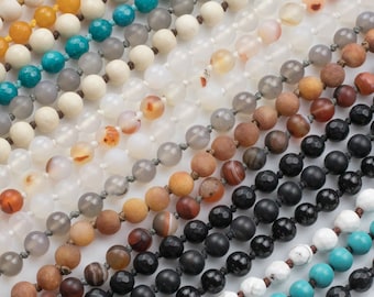May include: A collection of 10 strands of beaded necklaces in various colors, including turquoise, white, brown, and black. The beads are all round and have a matte finish.