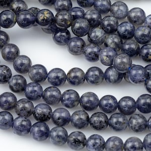 May include: A strand of blue and gray gemstone beads. The beads are round and have a slightly speckled appearance.
