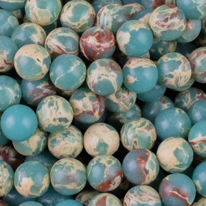 May include: A collection of round, polished beads in shades of teal, cream, and reddish-brown. The beads have a marbled appearance, with the colors swirling together. These beads are suitable for jewelry making.