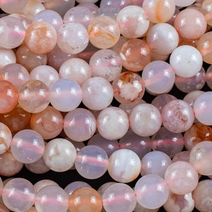 May include: A strand of pink and white agate beads. The beads are round and have a smooth, polished finish. They are ideal for making jewellery or other crafts.