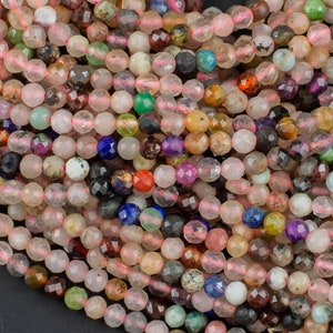 May include: A strand of pink, faceted gemstone beads with a mix of other colors, including blue, green, and brown. The beads are all approximately the same size and are strung on a clear thread.