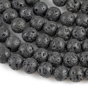 May include: A strand of black lava rock beads. The beads are round and have a rough, textured surface.