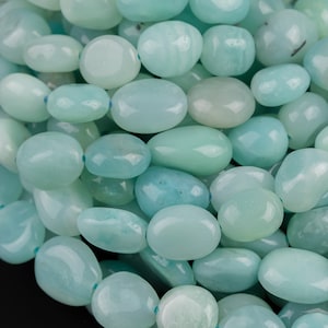 May include: A strand of smooth, oval-shaped, light blue green amazonite beads. The beads are tumbled and polished.