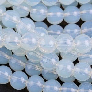 May include: A strand of translucent, light blue round glass beads. The beads are smooth and have a slightly iridescent finish.