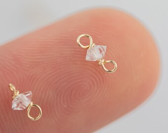 Op de afbeelding: Twee goudkleurige springringen met heldere, gefacetteerde kristallen kralen. De springringen zijn open en klaar om aan een sieradenproject te worden bevestigd.