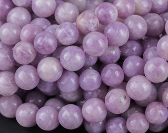 May include: A strand of lavender-colored gemstone beads. The beads are round and smooth, and they have a slightly translucent appearance.
