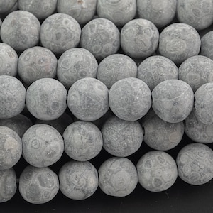 以下が含まれることがあります： まだら模様のグレーの丸い宝石ビーズのストランド。ビーズの直径は約10mmです。