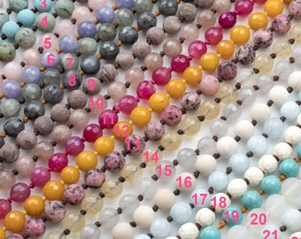 May include: A close-up of 25 strands of beads, each strand is a different color and type of stone. The strands are laid out in a row, with the numbers 1 through 25 written next to each strand.
