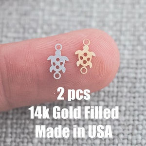 May include: Two 14k gold filled turtle charms, one silver and one gold, on a finger. 2 pcs 14k Gold Filled Made in USA