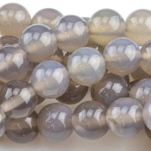 May include: A strand of round, gray agate beads. The beads are smooth and polished, with a slight translucence.