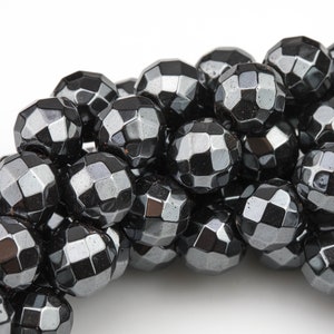 May include: A collection of faceted, black beads with a metallic sheen. The beads are round and have a geometric, multi-faceted design. The beads are likely for jewelry making.