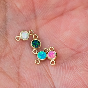 Puede incluir: Una cadena de oro con cinco pequeñas piedras redondas de ópalo de diferentes colores, incluyendo blanco, verde, azul y rosa.