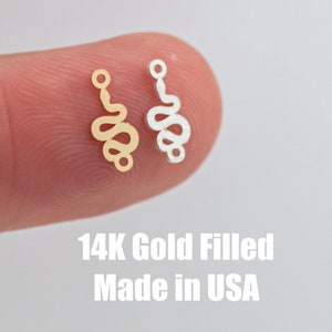 May include: Two small snake-shaped charms, one gold-filled and one silver, on a finger. 14K Gold Filled Made in USA.