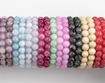 May include: A collection of 18 colorful beaded bracelets, each with a different color and texture. The bracelets are arranged in a row, with the colors transitioning from blue to green to purple to pink to red to white to black.