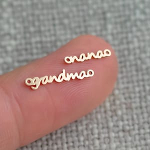 May include: Two gold-coloured metal charms, one with the word "grandma" and the other with the word "nana".