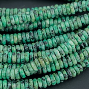 May include: A strand of green and black speckled gemstone beads. The beads are round and have a smooth, polished finish.